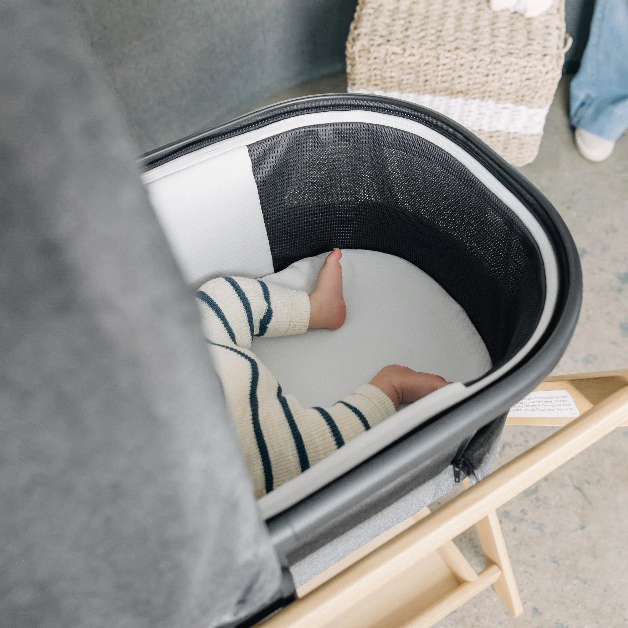 UPPAbaby bassinet carrycot interior showing baby resting on mattress with mesh ventilation sides.