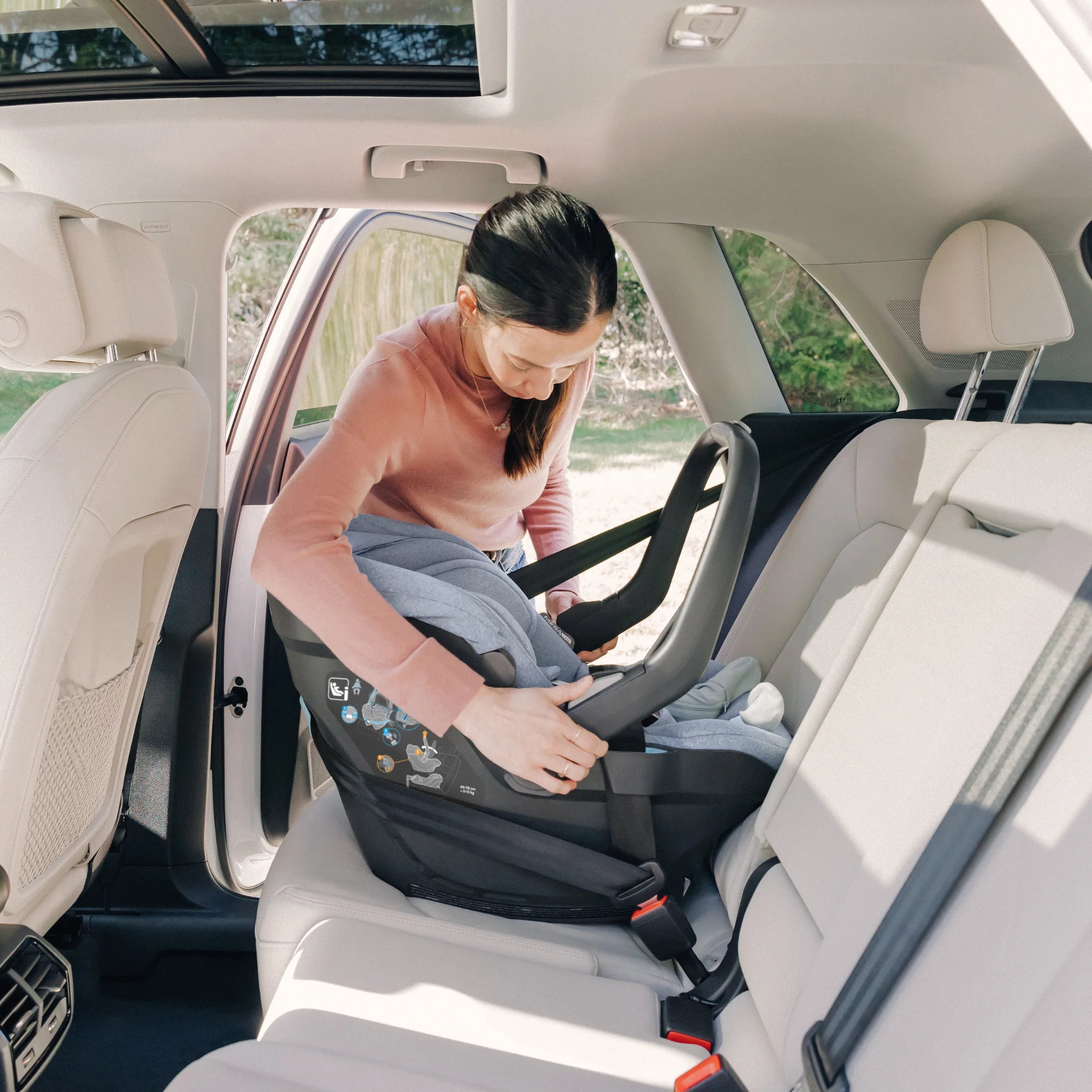 Woman securing Mesa car seat in car with setbelt.