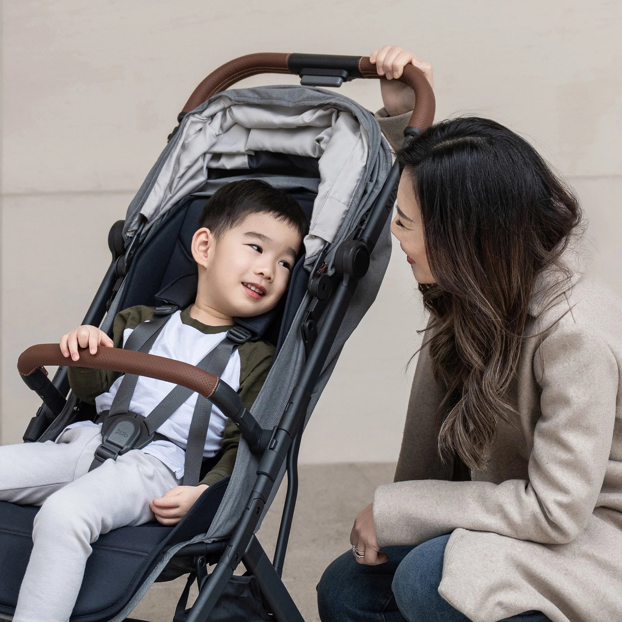 Child in the UPPAbaby travel pram with a woman sitting next to them, both smiling.