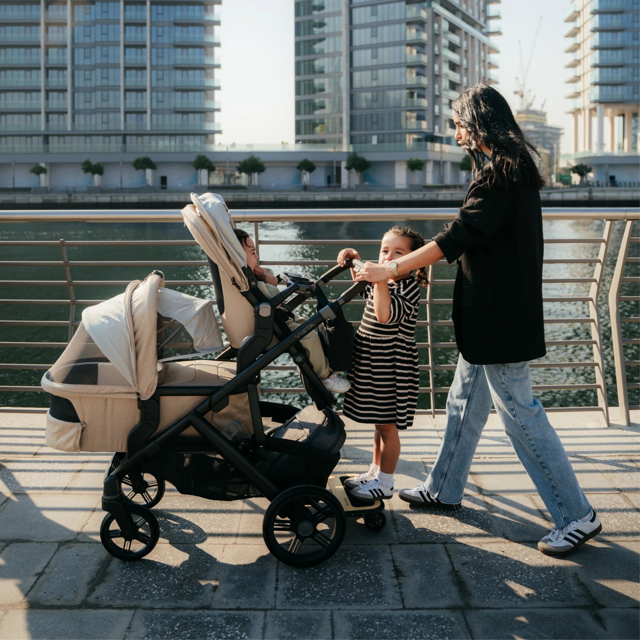 Woman pushing the Vista V3 in Liam with three children along a river on a sunny day.