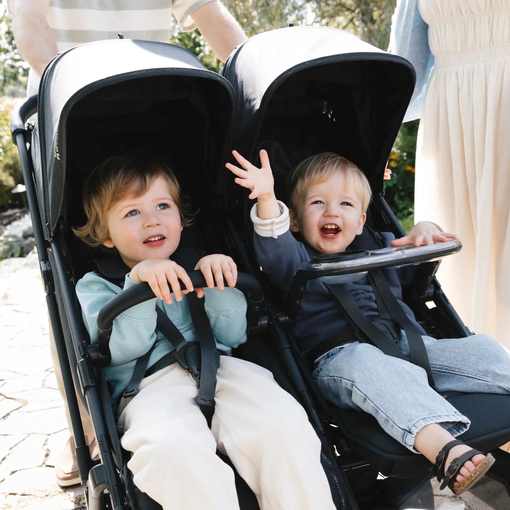 Two children sitting in a UPPAbaby Minu Duo double stroller with the snack tray attached.