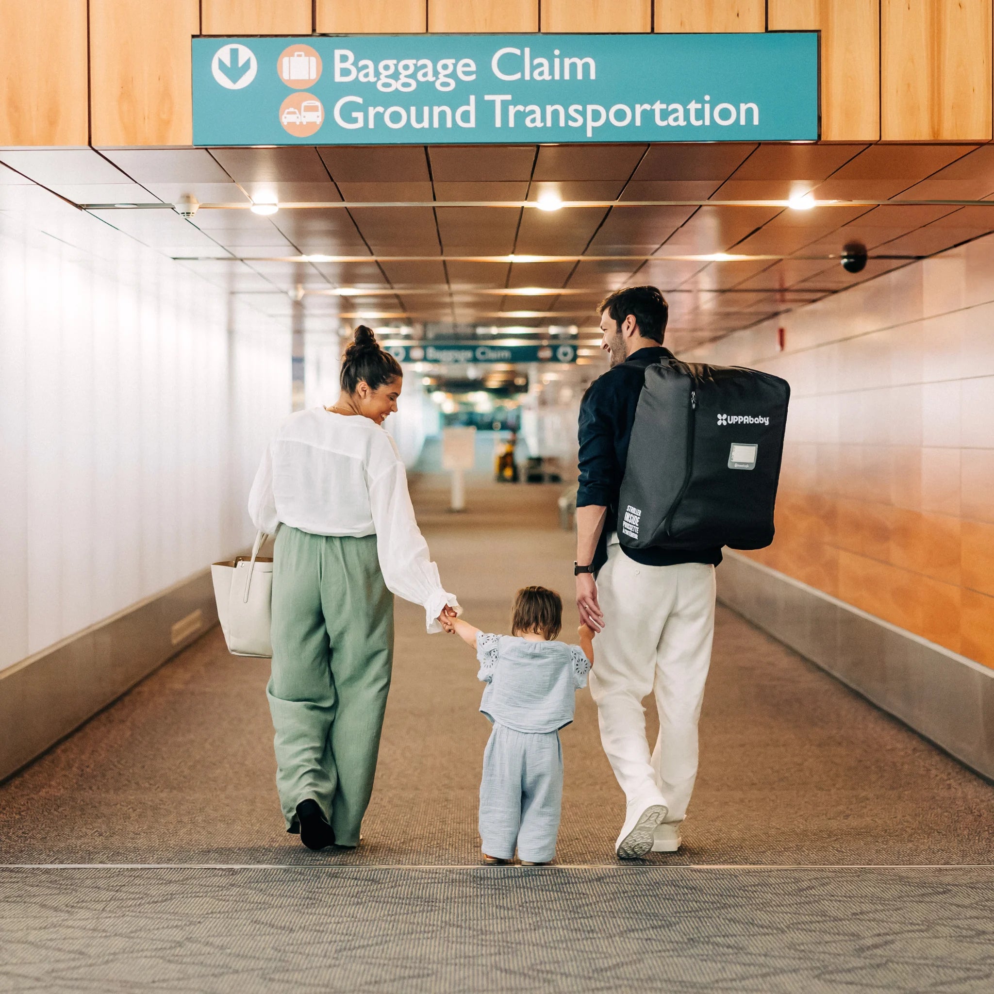 Family walking through airport with UPPAbaby Minu V3 Travel Bag worn as backpack, hands-free stroller travel bag
