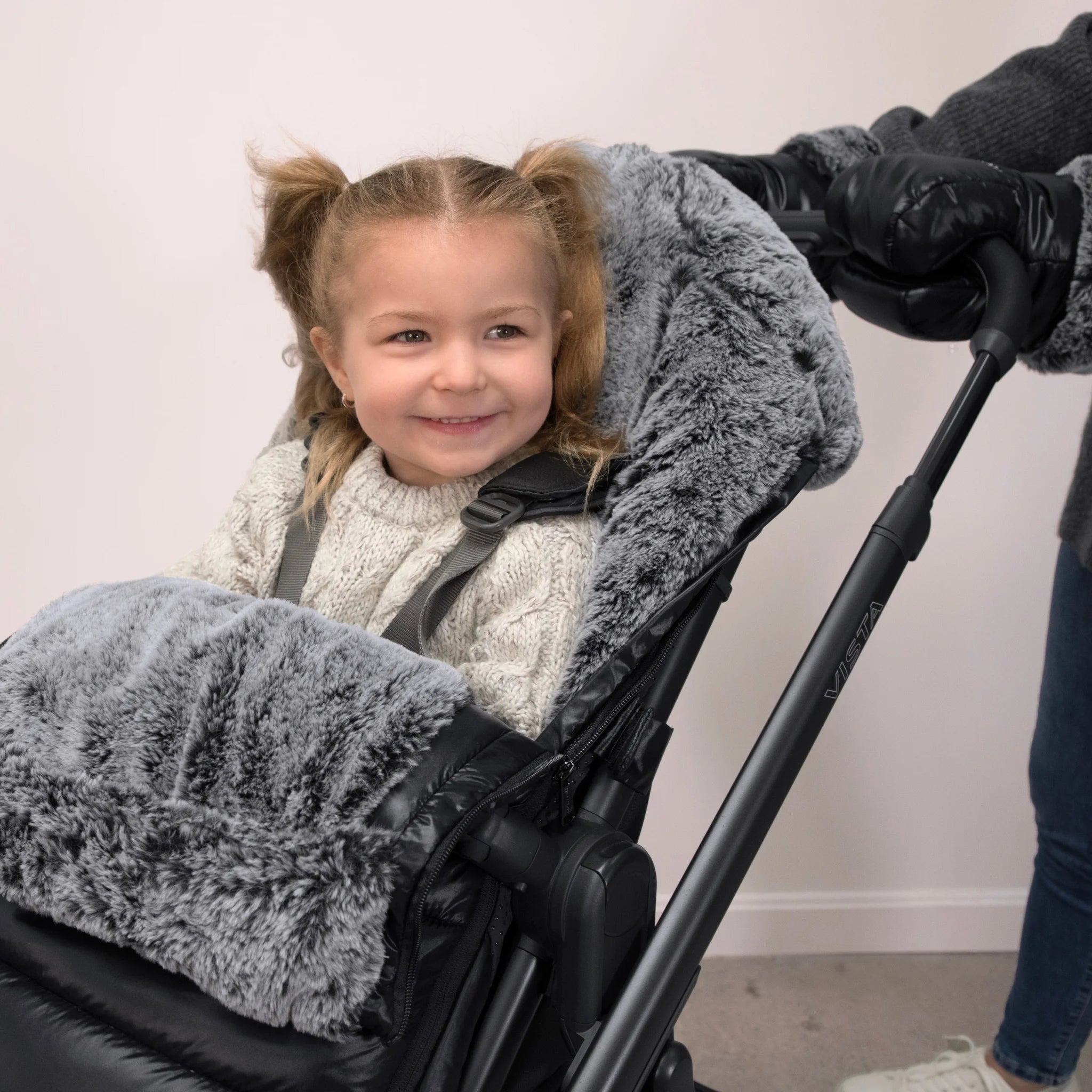 Girl smiling out of stroller with a cozy ganoosh luxe on it.
