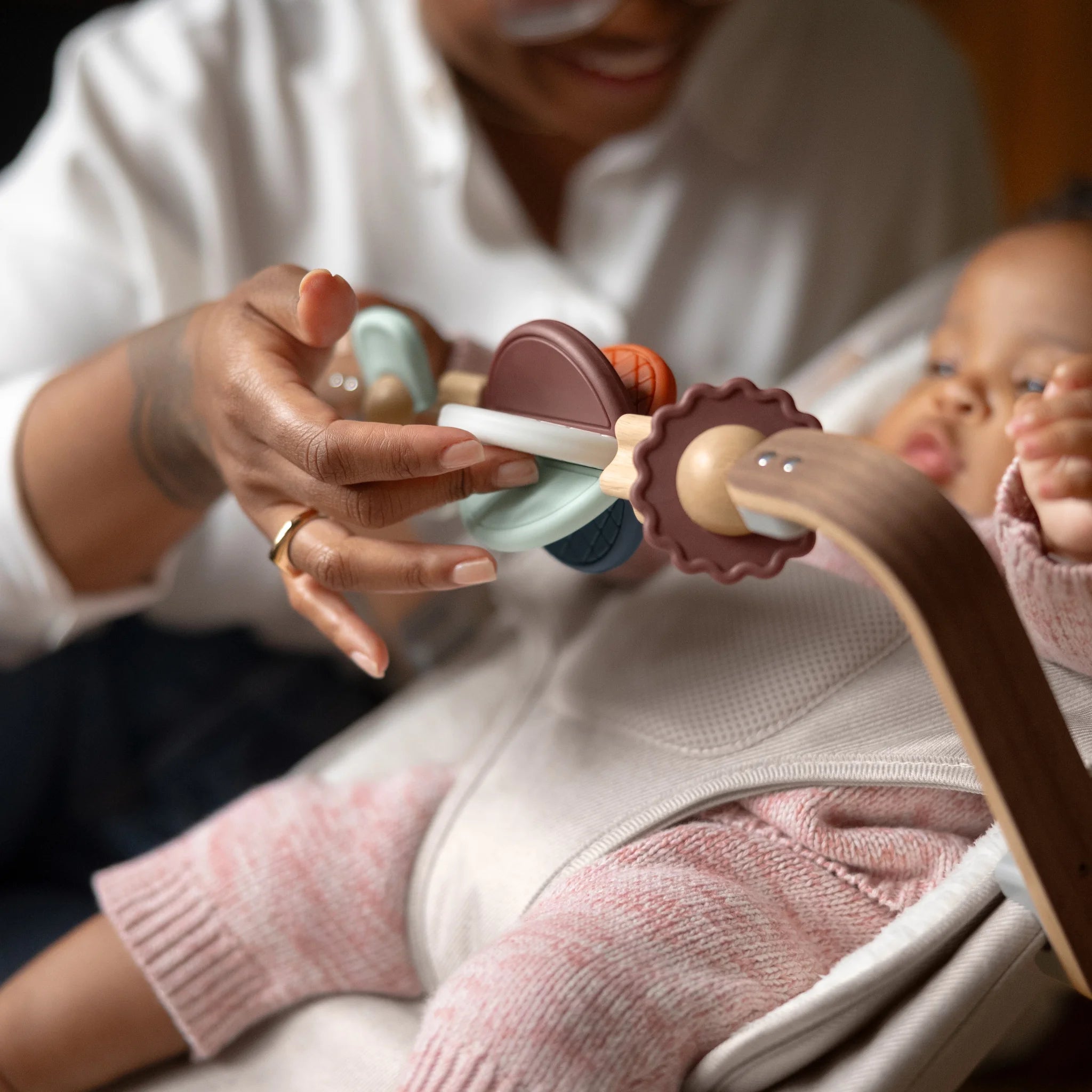 Mum smiling and fidgeting with mira wonderwheel toy bar, entertaining baby.