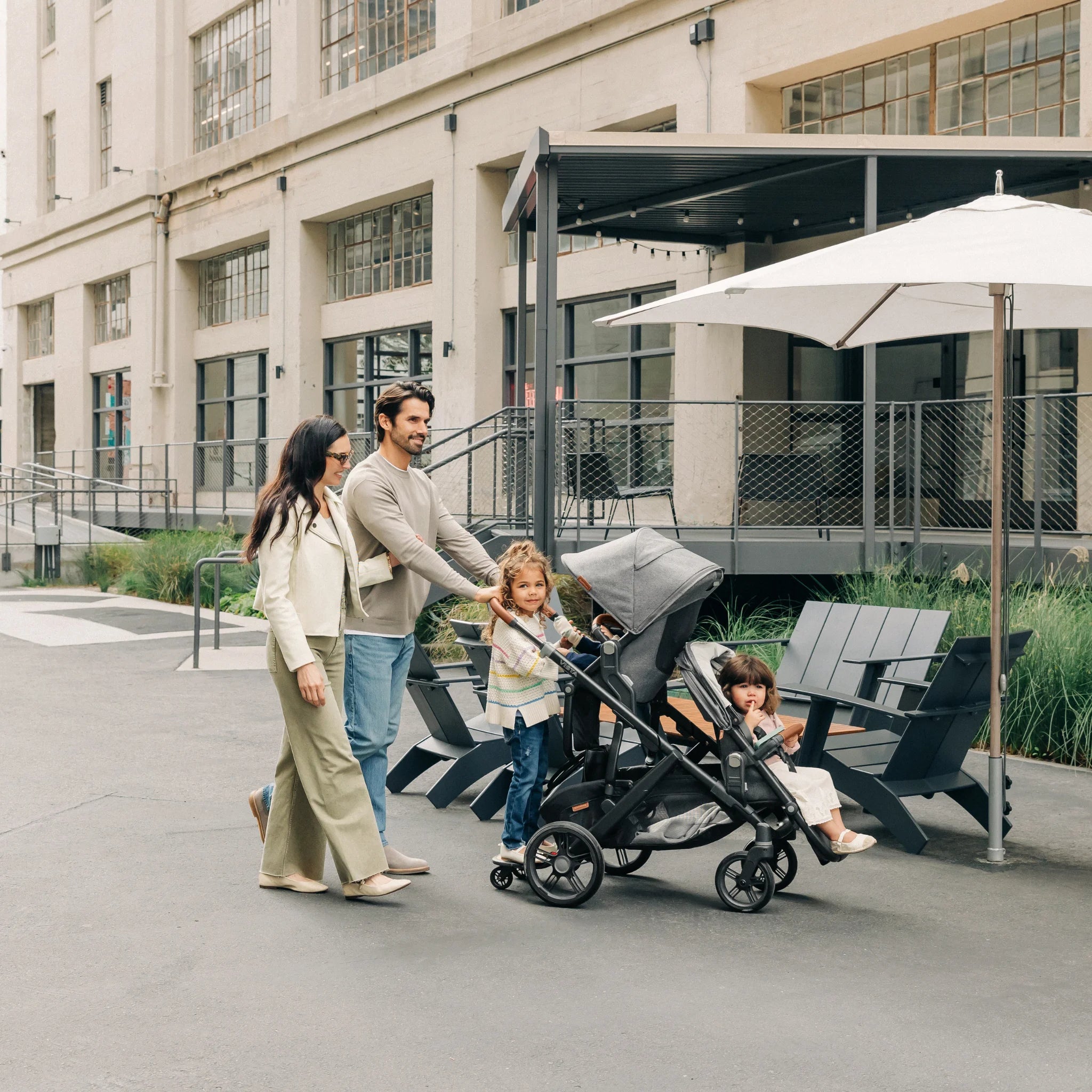 Parents smiling and pushing vista buggy with kids smiling in it, outdoors