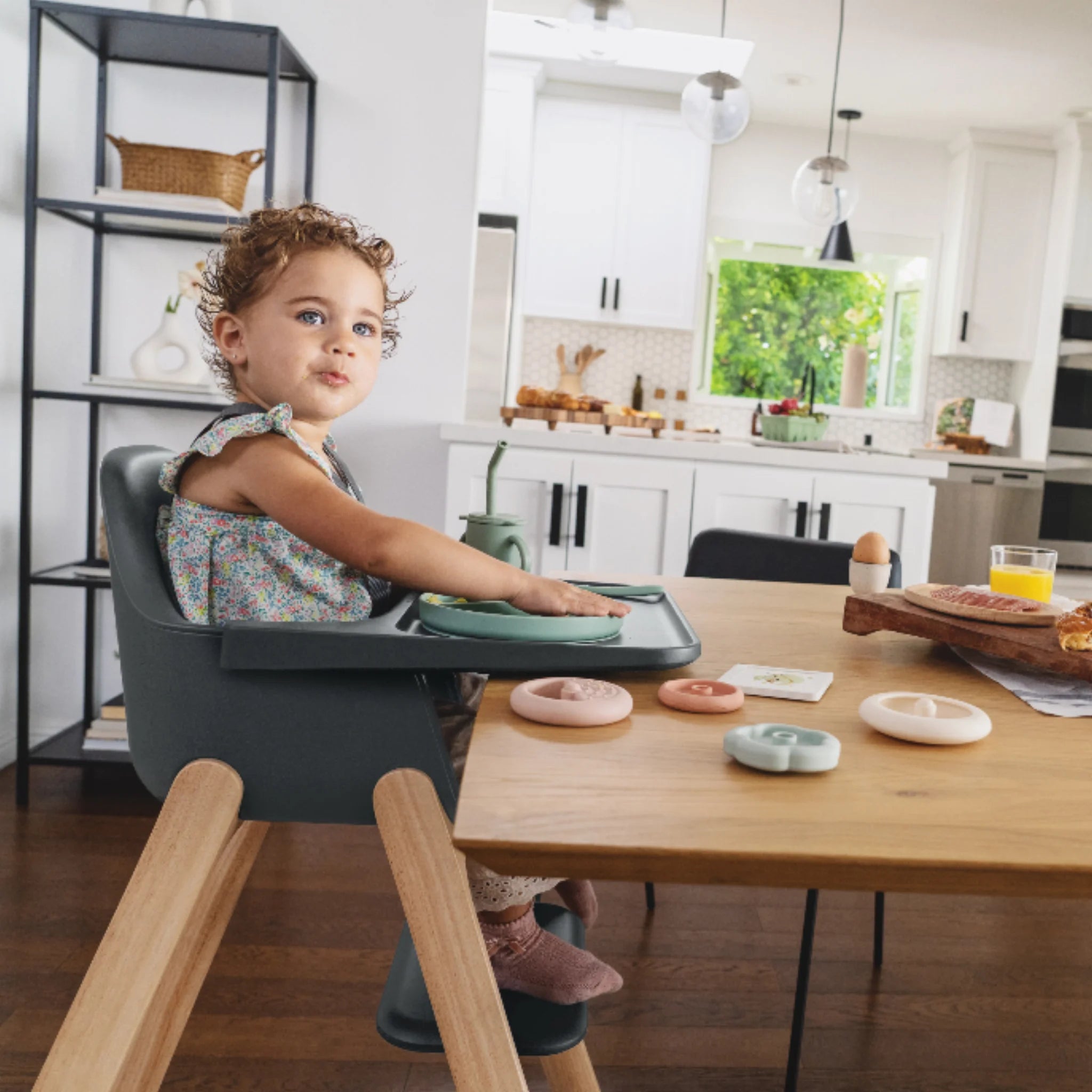 Toddler sitting in the Jake Ciro high chair at a wooden dining table in a bright kitchen.
