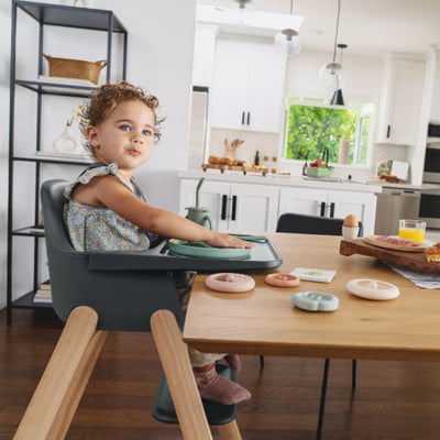 Toddler sitting in the Jake Ciro high chair at a wooden dining table in a bright kitchen.