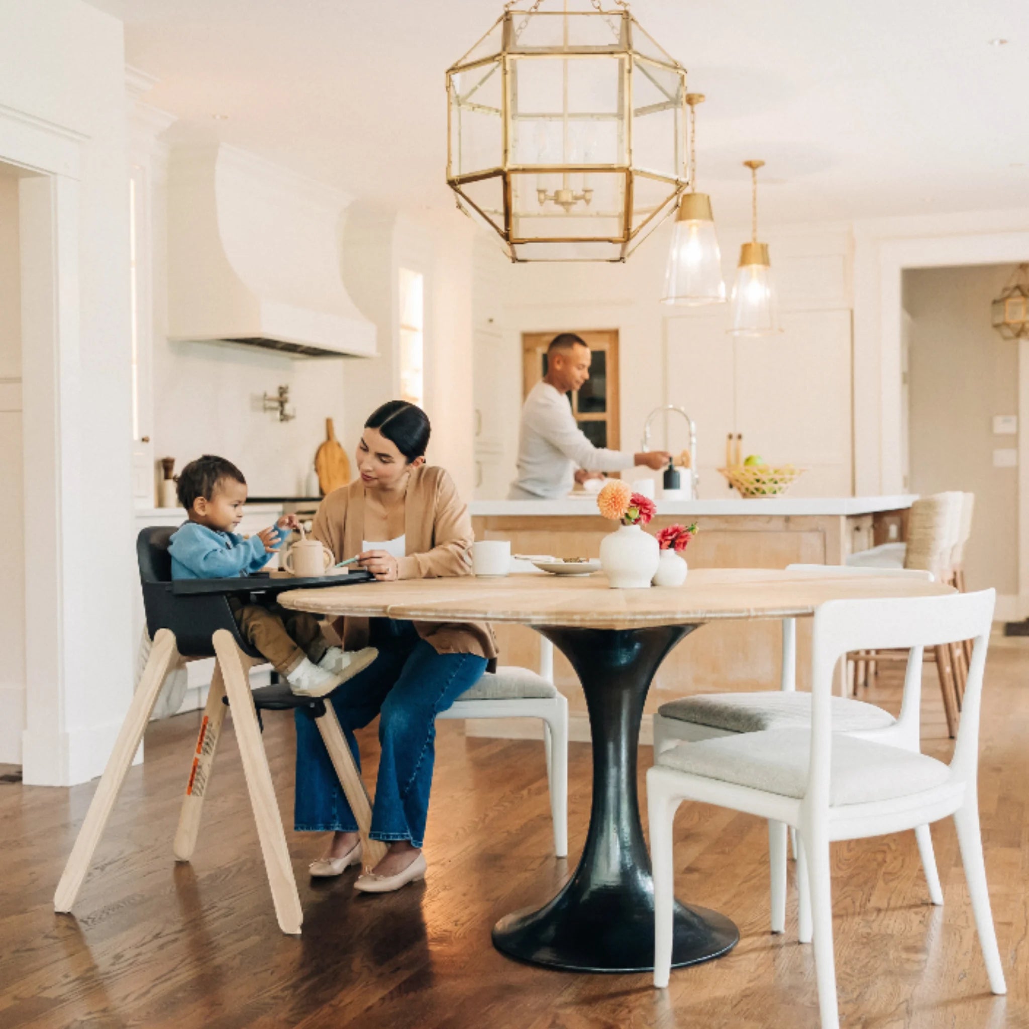 Parent and toddler at a round dining table, with the toddler seated in the Jake Ciro high chair in a bright open-plan kitchen