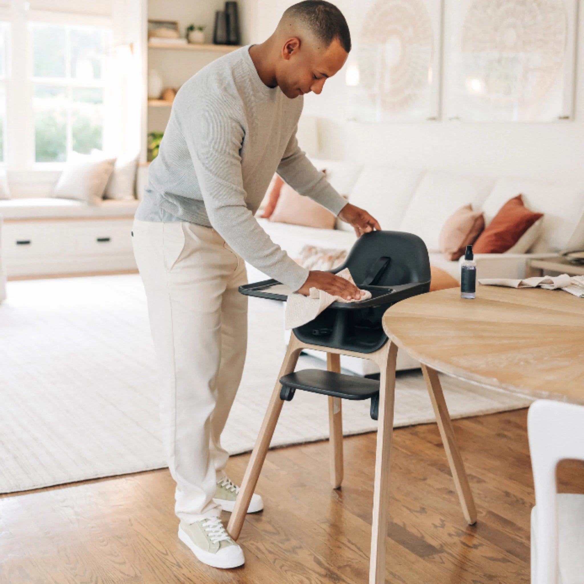 Adult wiping down the Jake Ciro high chair beside a dining table in a bright modern living space