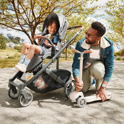 Man pushing a Cruz V3 pram with a child sitting inside on a paved path.