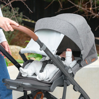 Baby in the Cruz V3 newborn mode with extended sunshade outdoors.