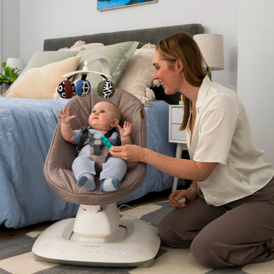 Mum playing with baby looking at mobile in the Mamroo smart swing.