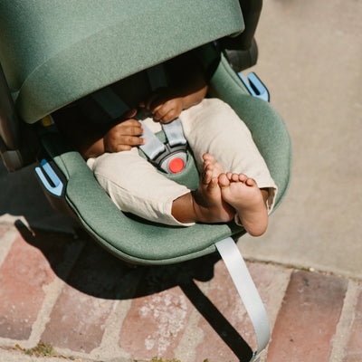 Baby toes peeking out of the UPPAbaby Mesa car seat with sunshade extended on sunny day.