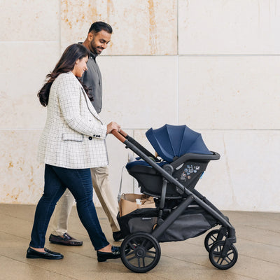 Parents pushing the UPPAbaby Vista as a travel system with the Noa car seat attached.