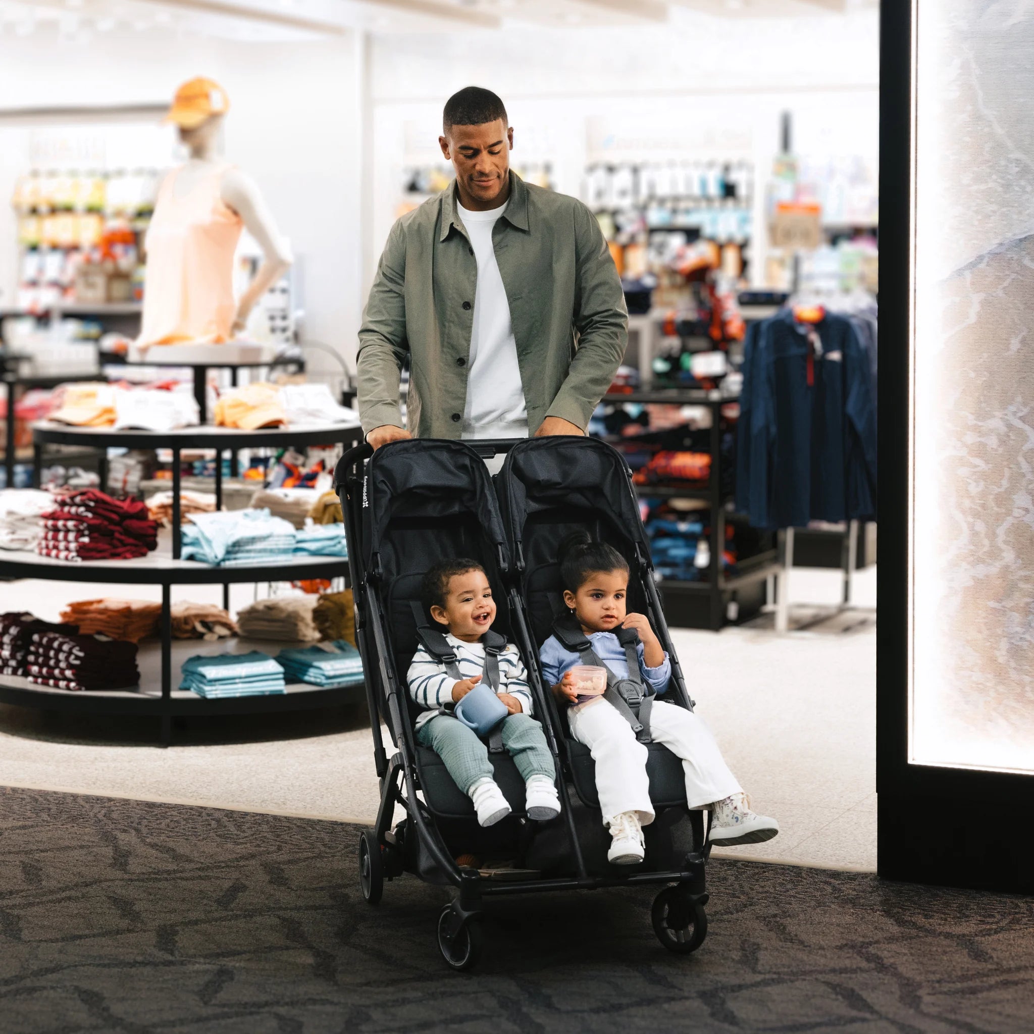 Dad pushing the Minu Duo with two toddlers through an airport.