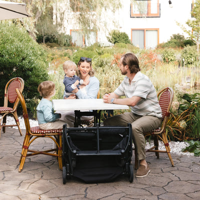 Family sitting at outdoor restaurant table with the Minu Duo folded neatly under the table.