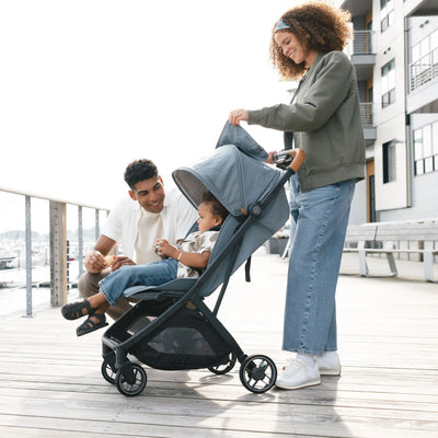 Woman checking on child through mesh peek-a-boo window on the Minu V3 stroller while on a boardwalk.