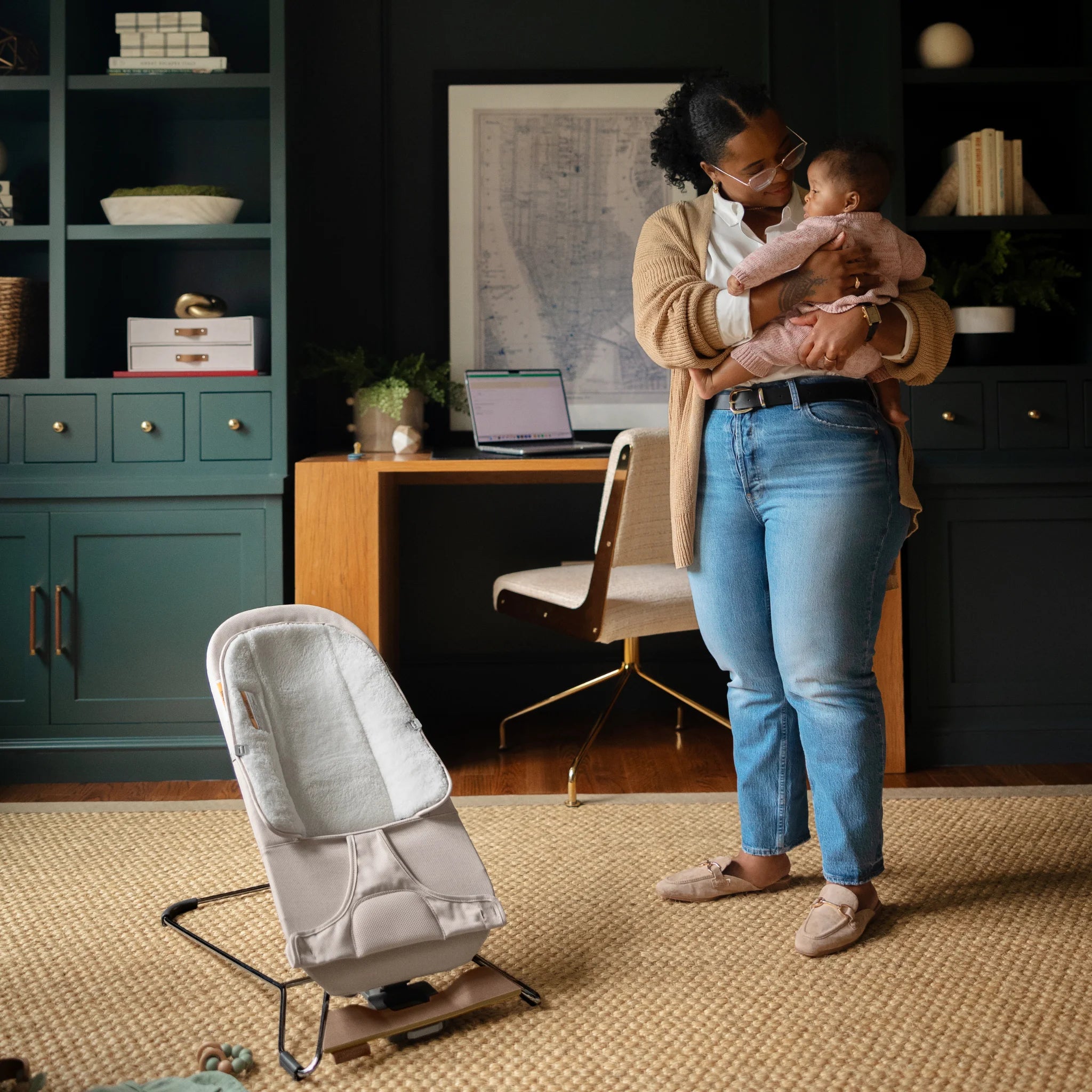 Parent holding baby beside the UPPAbaby Mira baby bouncer in Charlie