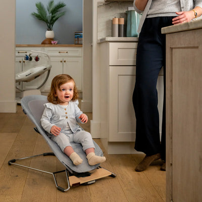 Toddler sitting in the UPPAbaby Mira baby bouncer in Stella at home
