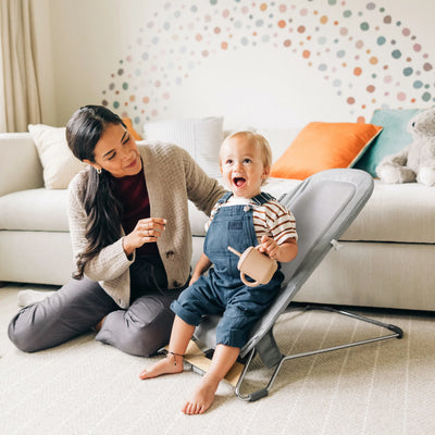 Parent playing with toddler in the UPPAbaby Mira baby bouncer in Stella