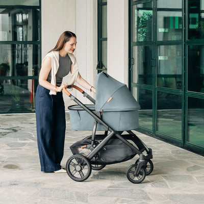UPPAbaby pram with mum pushing baby in carrycot in the Dillan fashion outdoors.