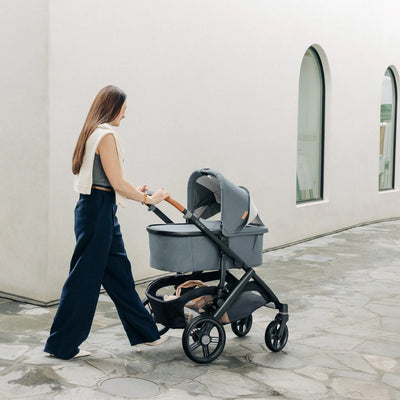 Woman pushing Vista pram around the corner with the top ventilation panel open.
