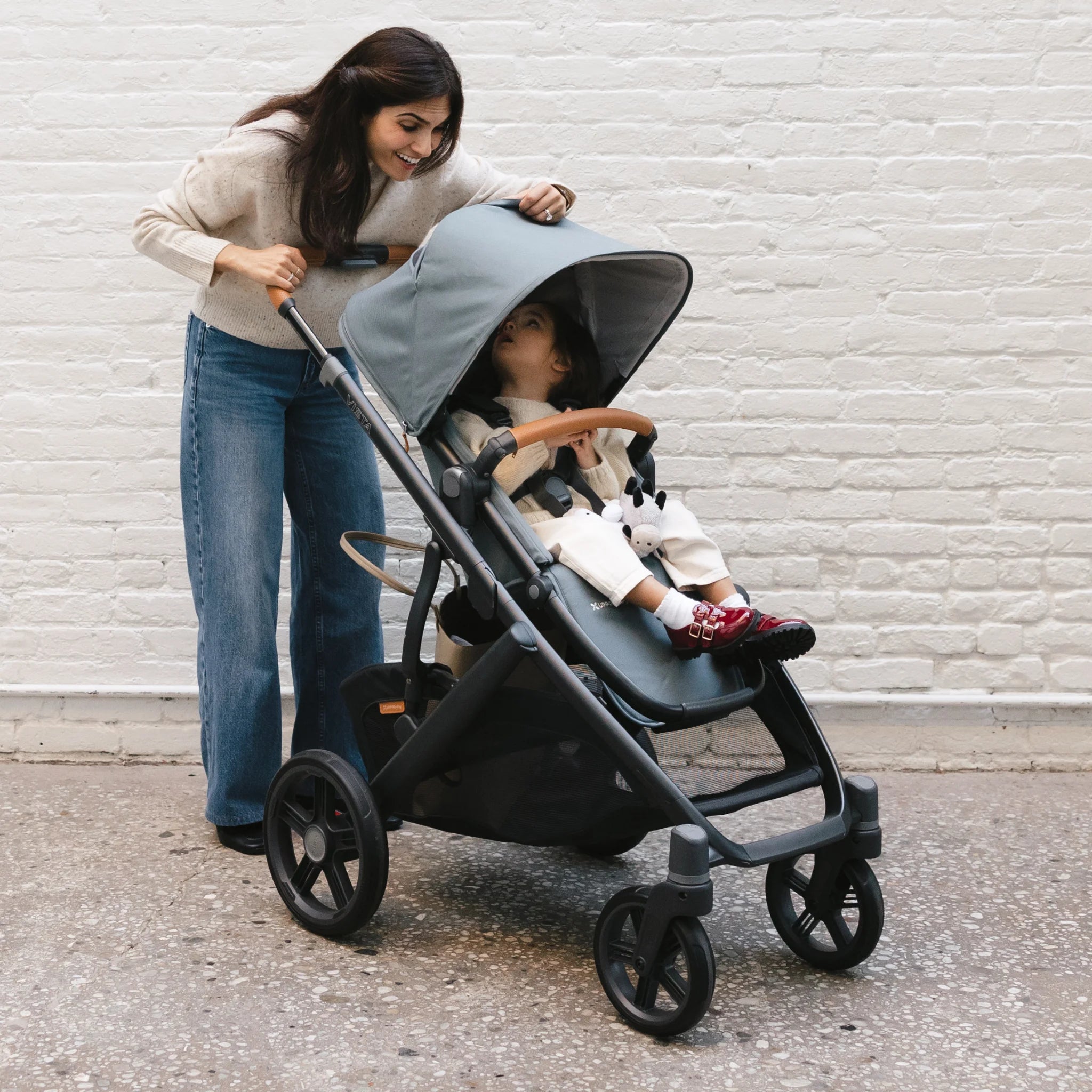 Mum looking at toddler in Vista through the peek-a-boo window in front of a white brick wall.