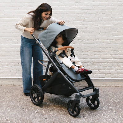 Mum looking at toddler in Vista through the peek-a-boo window in front of a white brick wall.