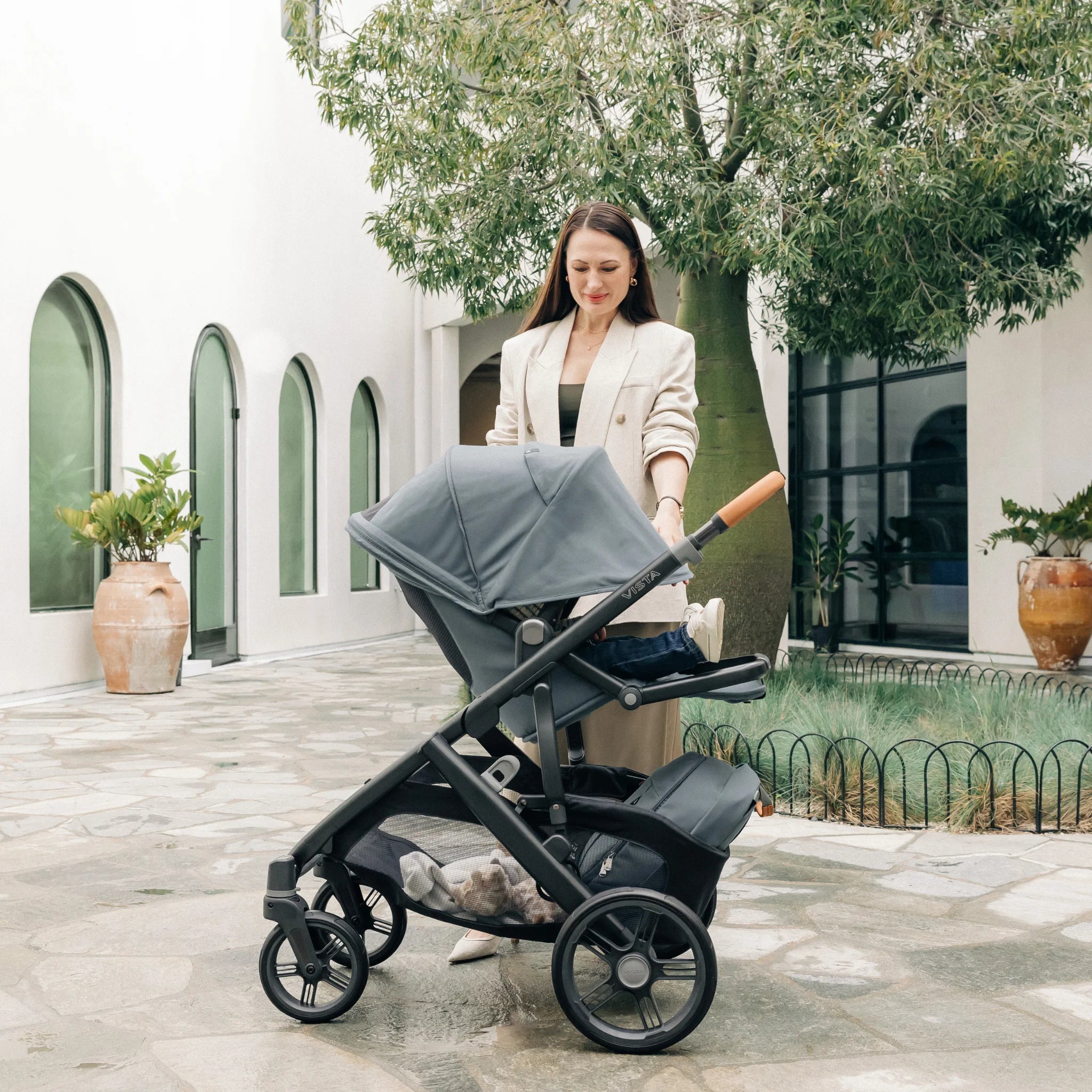 Woman smiling extending the UPF50+ Canopy to cover her toddler in the Vista V3.