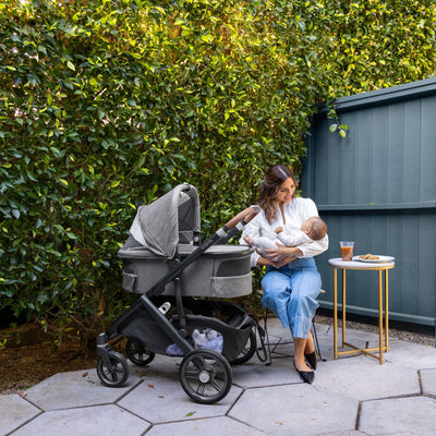 Woman holding baby while out for a coffee with her Vista next to her.