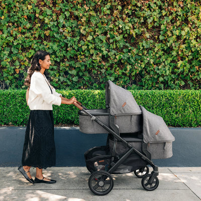 Mum pushing the Vista stroller in twin mode for newborns.