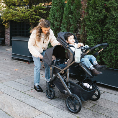 Woman tending to child in RumbleSeat on the Vista stroller.