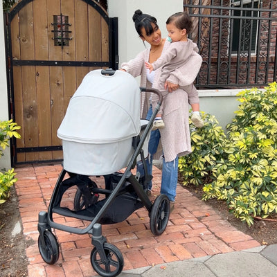 Mum holding baby on hip and chatting to baby in Savannah carrycot.