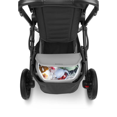 Rear view of a black stroller with a grey UPPAbaby Bevvy cooler bag in the under-seat basket, filled with ice and drinks, on a white background.
