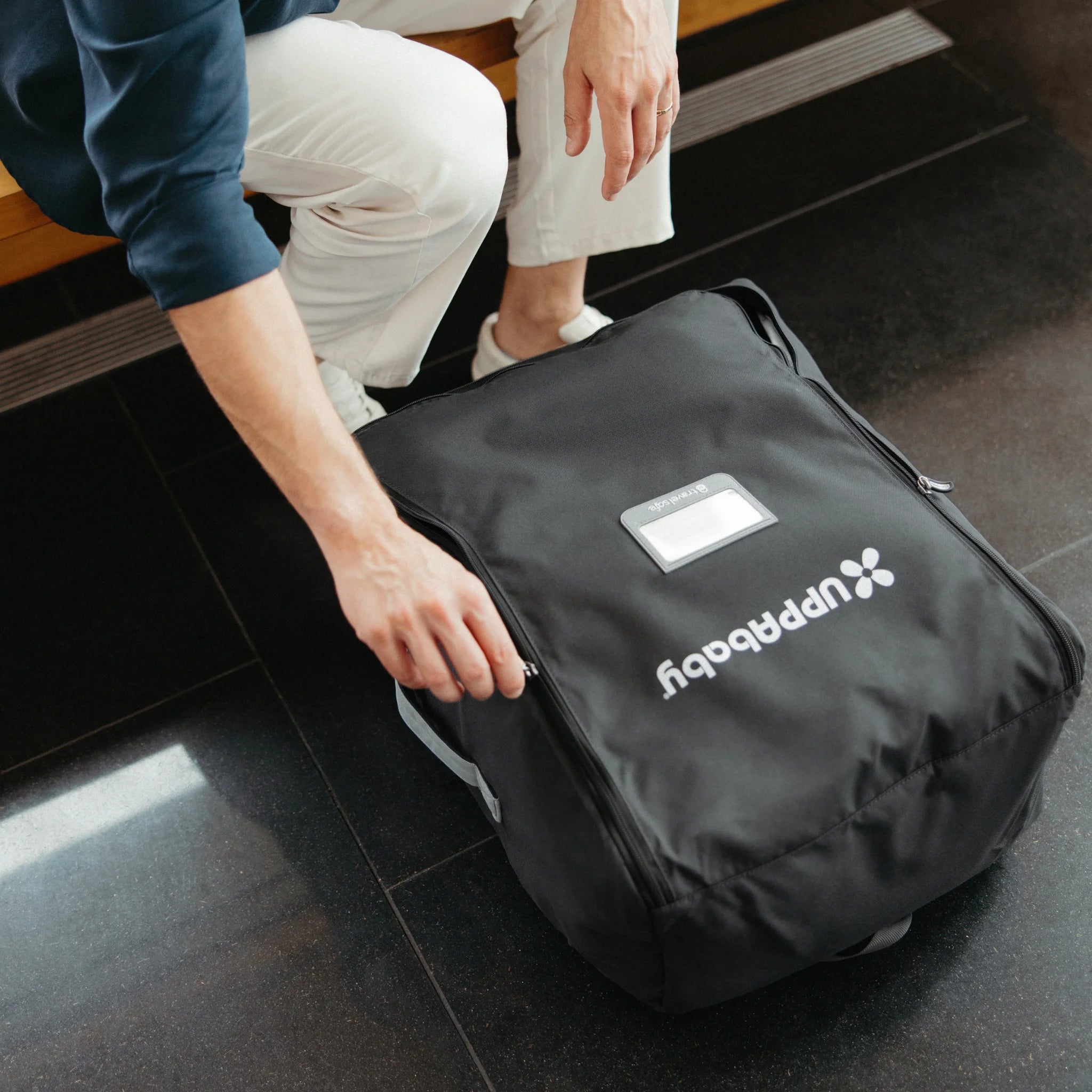 Person unzipping UPPAbaby Minu V3 Travel Bag on airport floor, protective stroller travel bag for flying