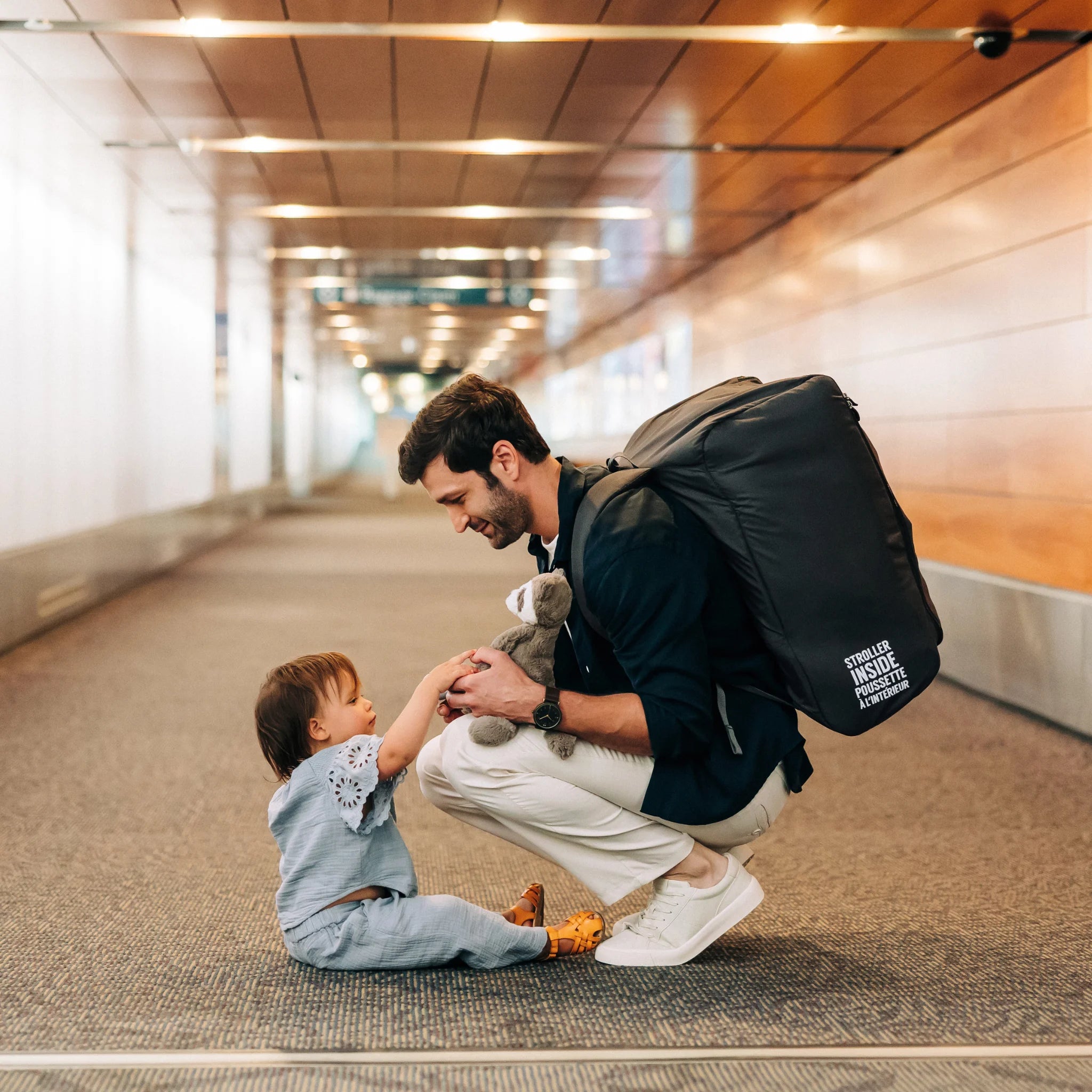 Parent wearing UPPAbaby Minu V3 Travel Bag as backpack in airport, carrying stroller travel bag