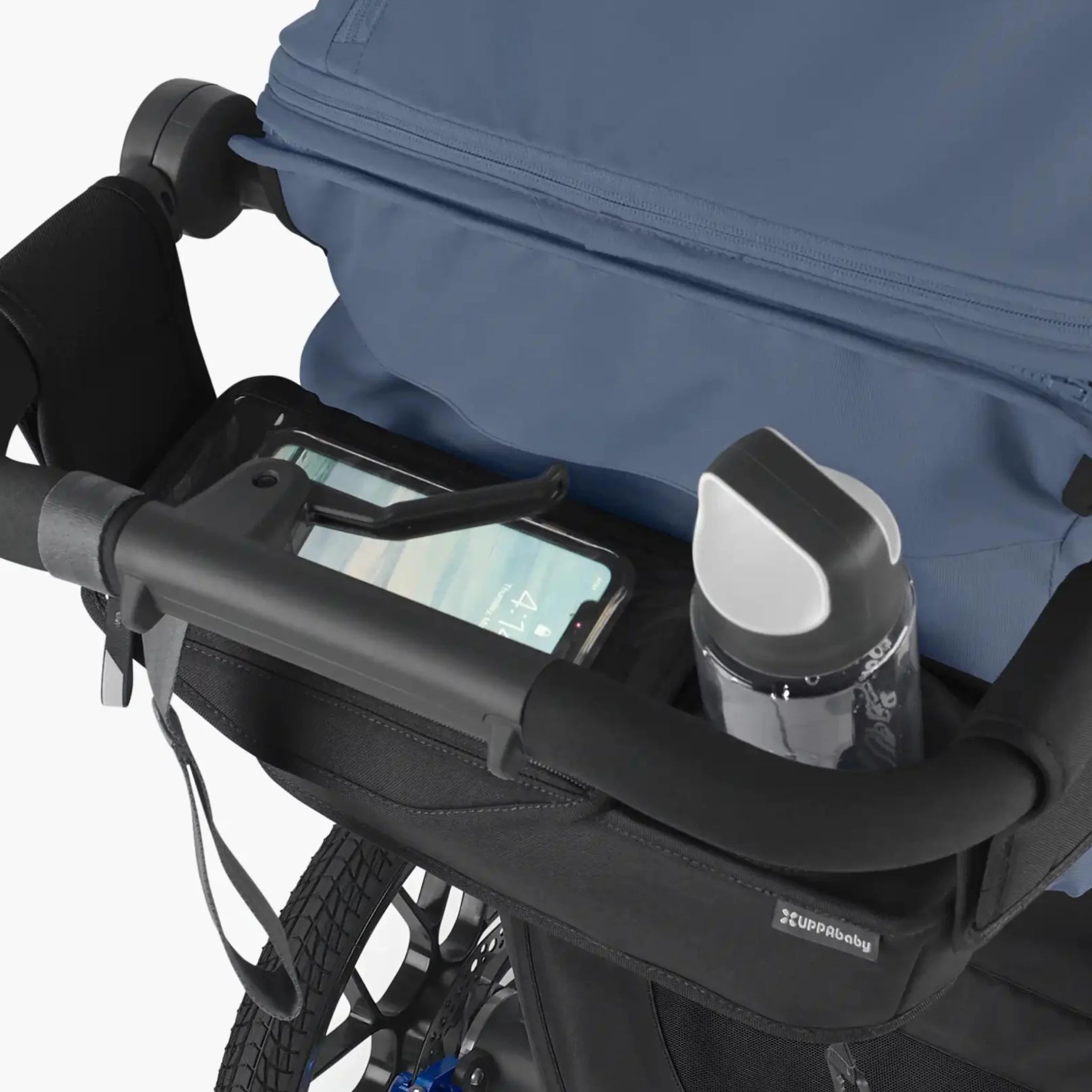 Close-up of UPPAbaby Ridge parent console attached to the handlebar, holding a phone and water bottle on a stroller.