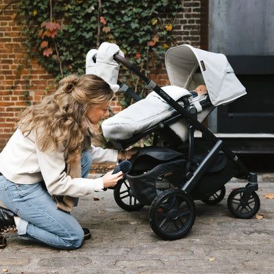 Mum taking out hat out of the bottom of the vista buggy,outside. 