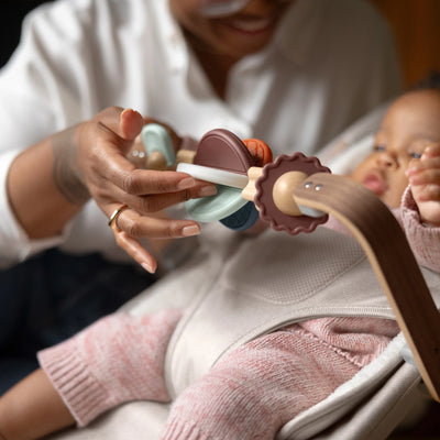 Mum smiling and fidgeting with mira wonderwheel toy bar, entertaining baby. 