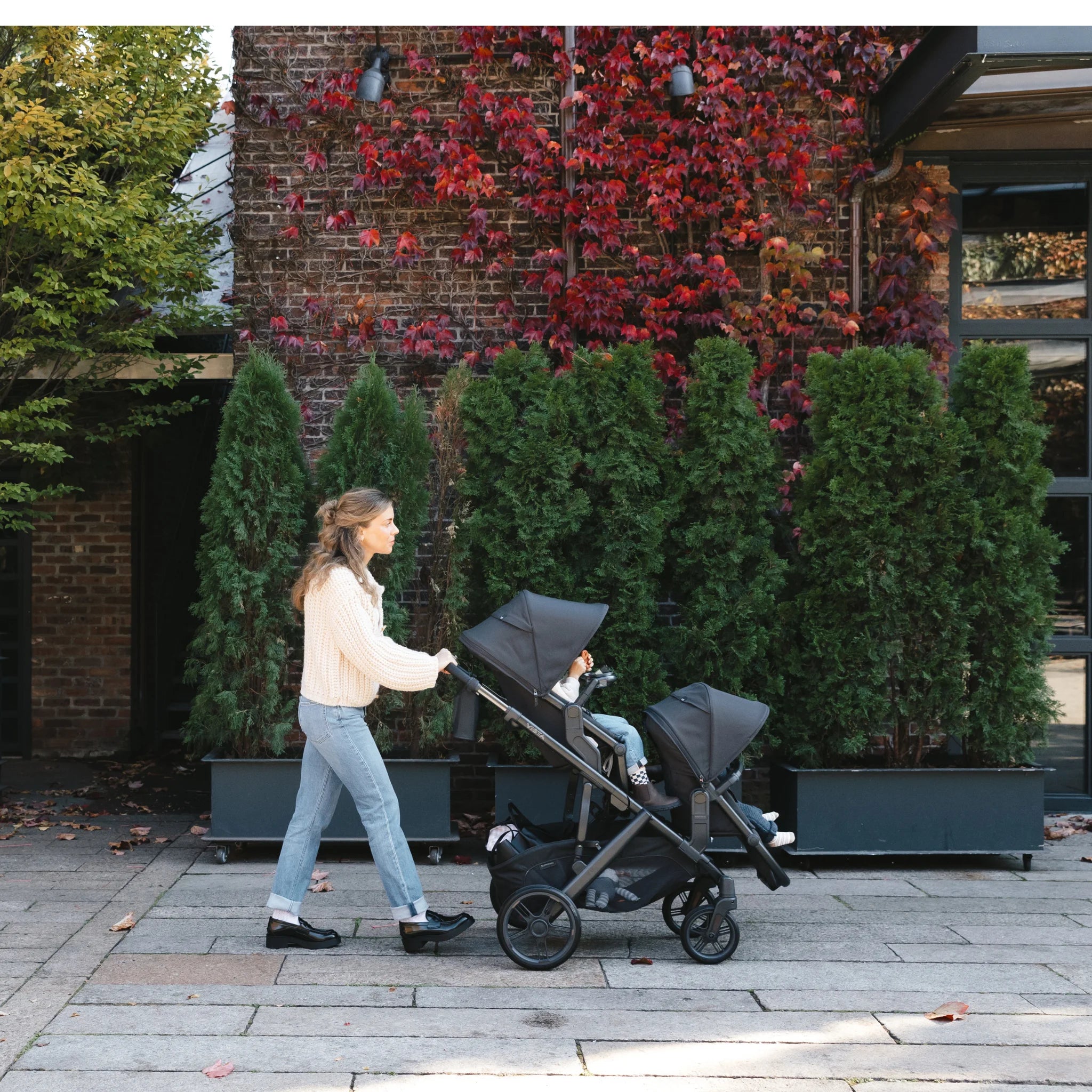 Mum pushing double rumbleseat stroller in colour jake outdoors. 