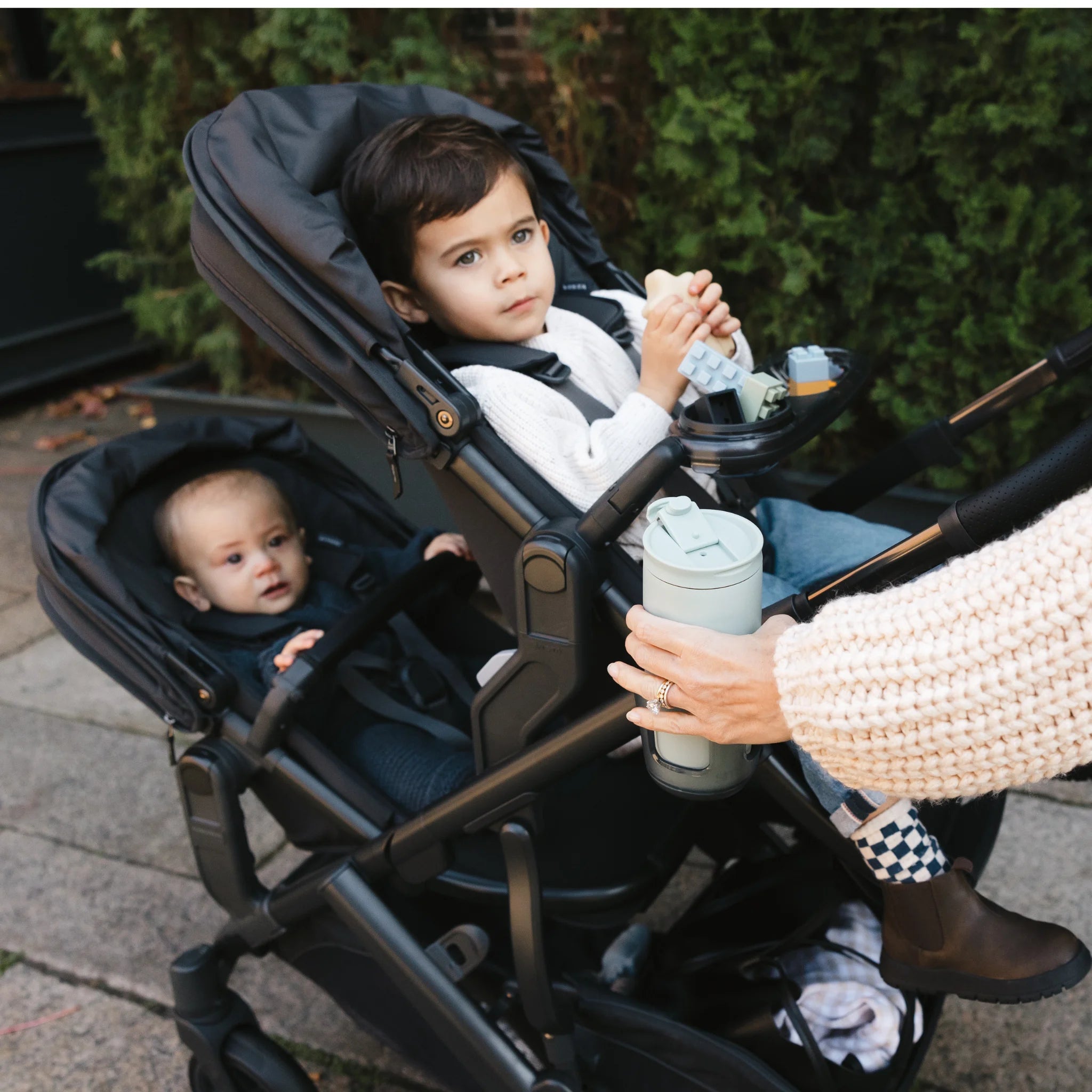 Kids looking into distance from the double rumbleseat stroller outdoors. 