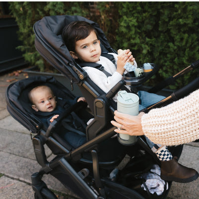 Kids looking into distance from the double rumbleseat stroller outdoors. 